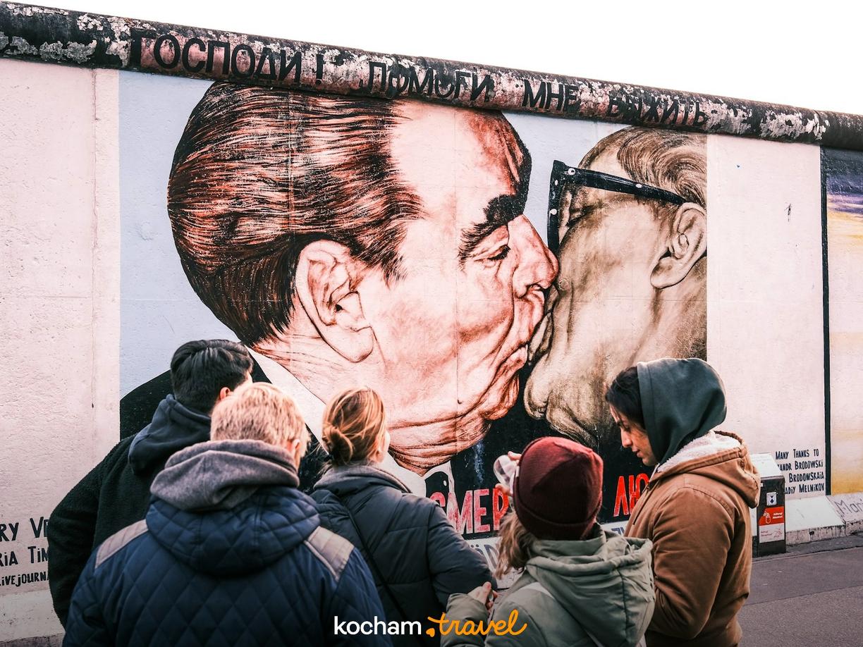 Turyści oglądają słynny pocałunek braterski na East Side Gallery w Berlinie.