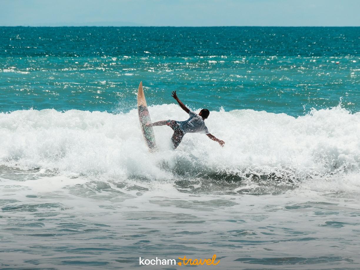 Surfer balansujący na szczycie spienionej fali w błękitnym oceanie.