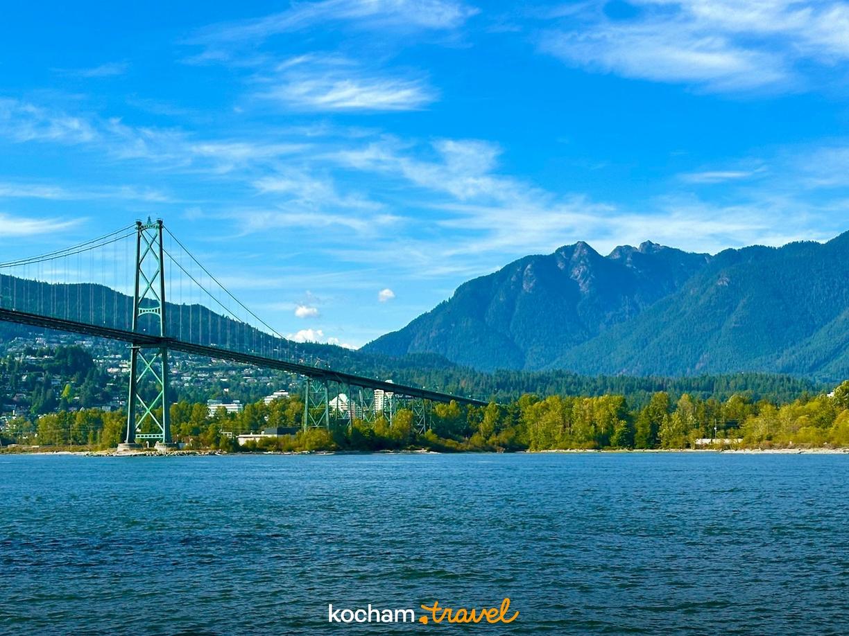 Most Lions Gate, Vancouver, błękitna woda i zalesione góry.