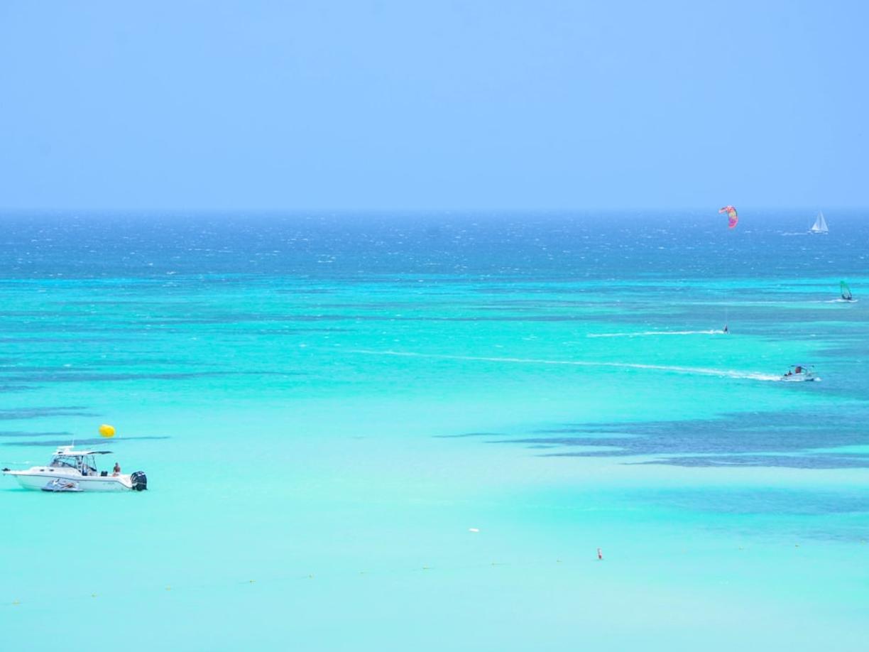Krystalicznie czyste turkusowe morze, łodzie, kitesurfing i żaglówka.