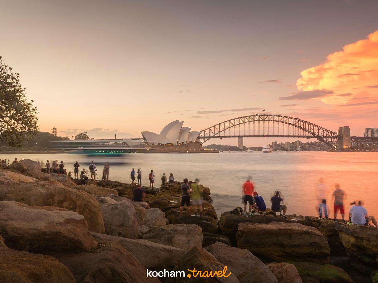 Fotografowie uwieczniający zachód słońca nad Operą i Mostem w Sydney.