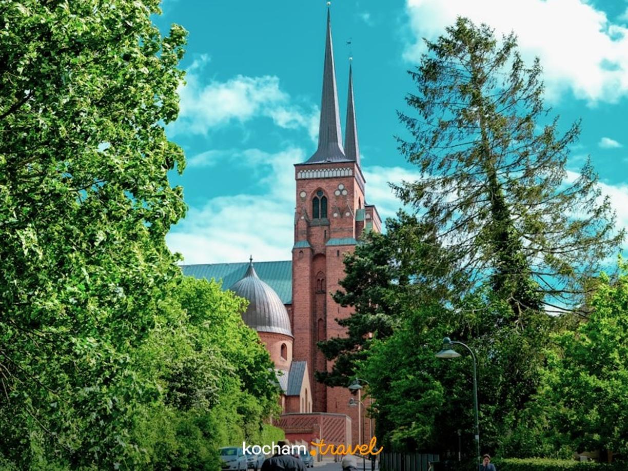 Katedra w Roskilde, Dania, gotycka architektura, uliczka, zieleń, ludzie.
