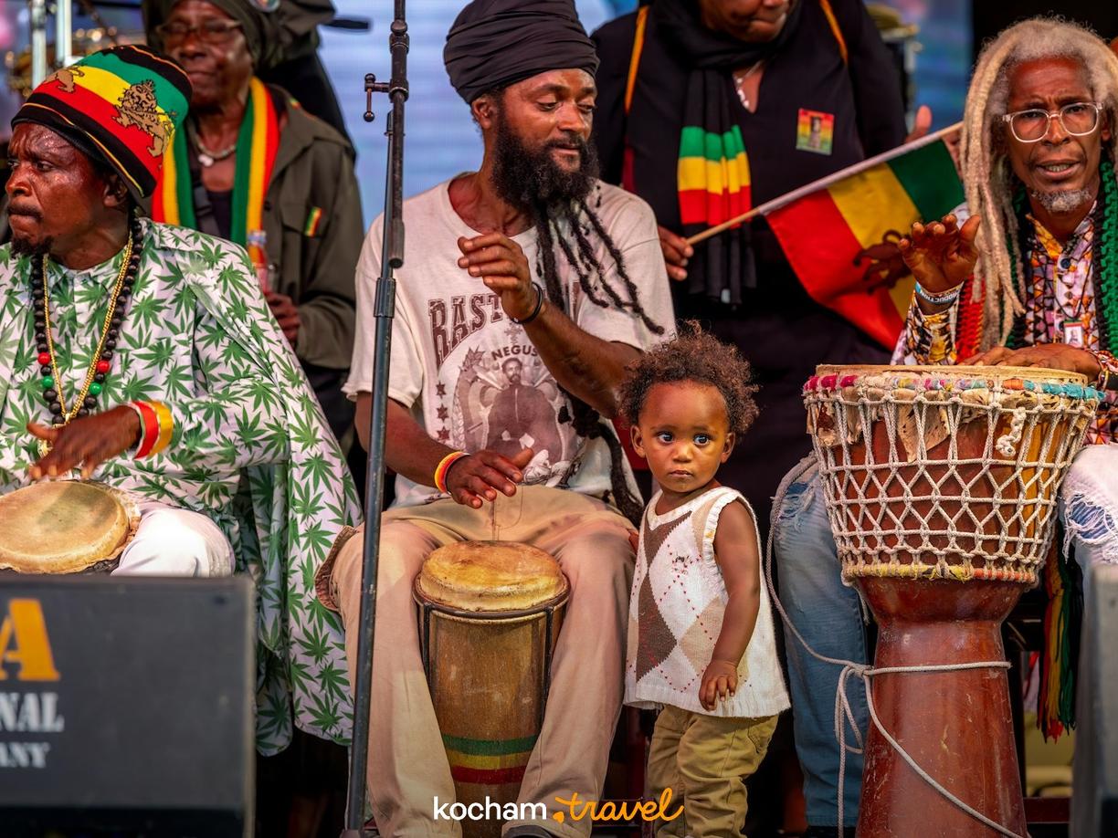 Rastafariańscy muzycy grający na bębnach, z dzieckiem obok.