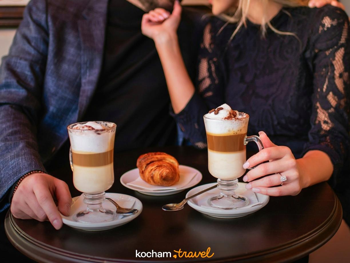 Zakochana para delektuje się kawą i rogalikiem w przytulnej kawiarni.