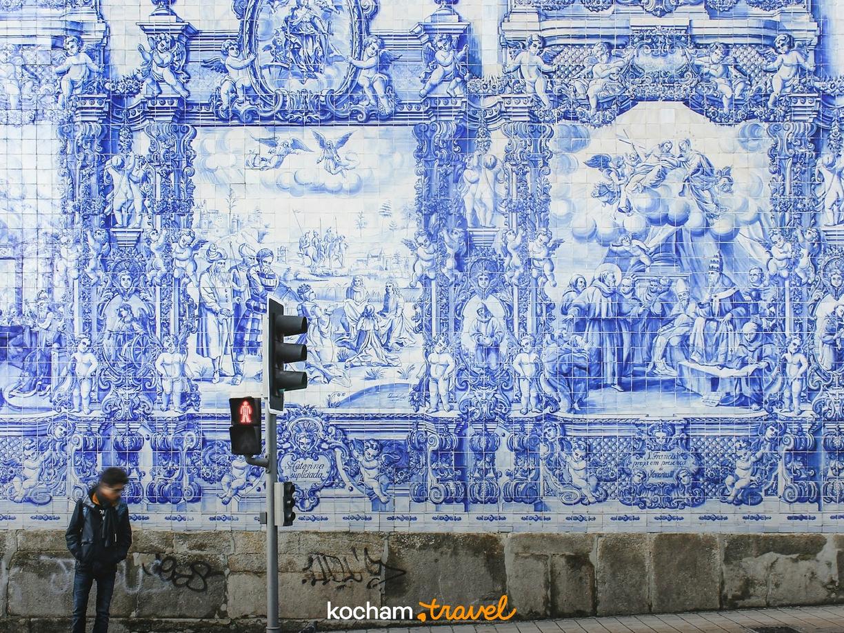 Niebiesko-białe azulejos na ścianie przedstawiające sceny historyczne w Porto.