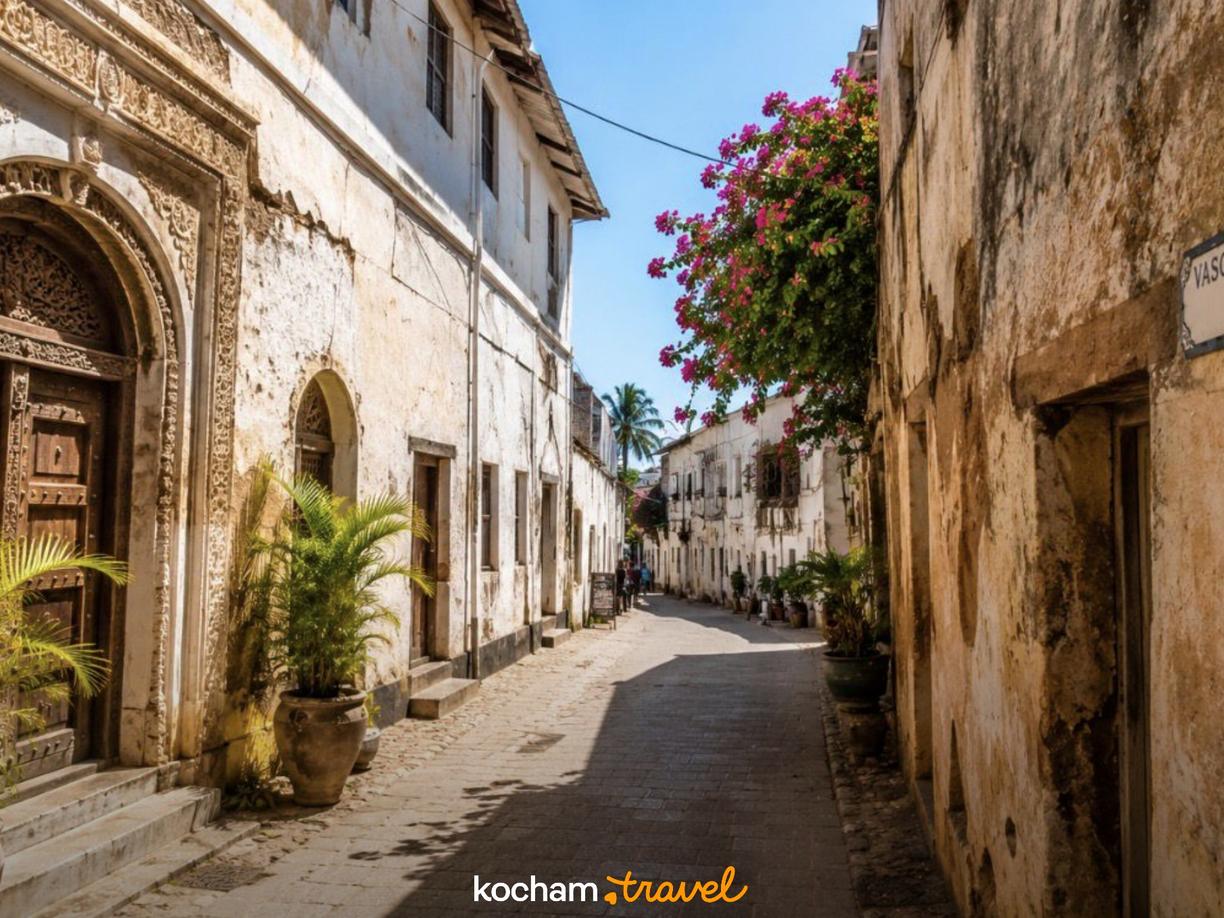 Kamienna uliczka z rzeźbionymi drzwiami i bugenwillą na Zanzibarze.