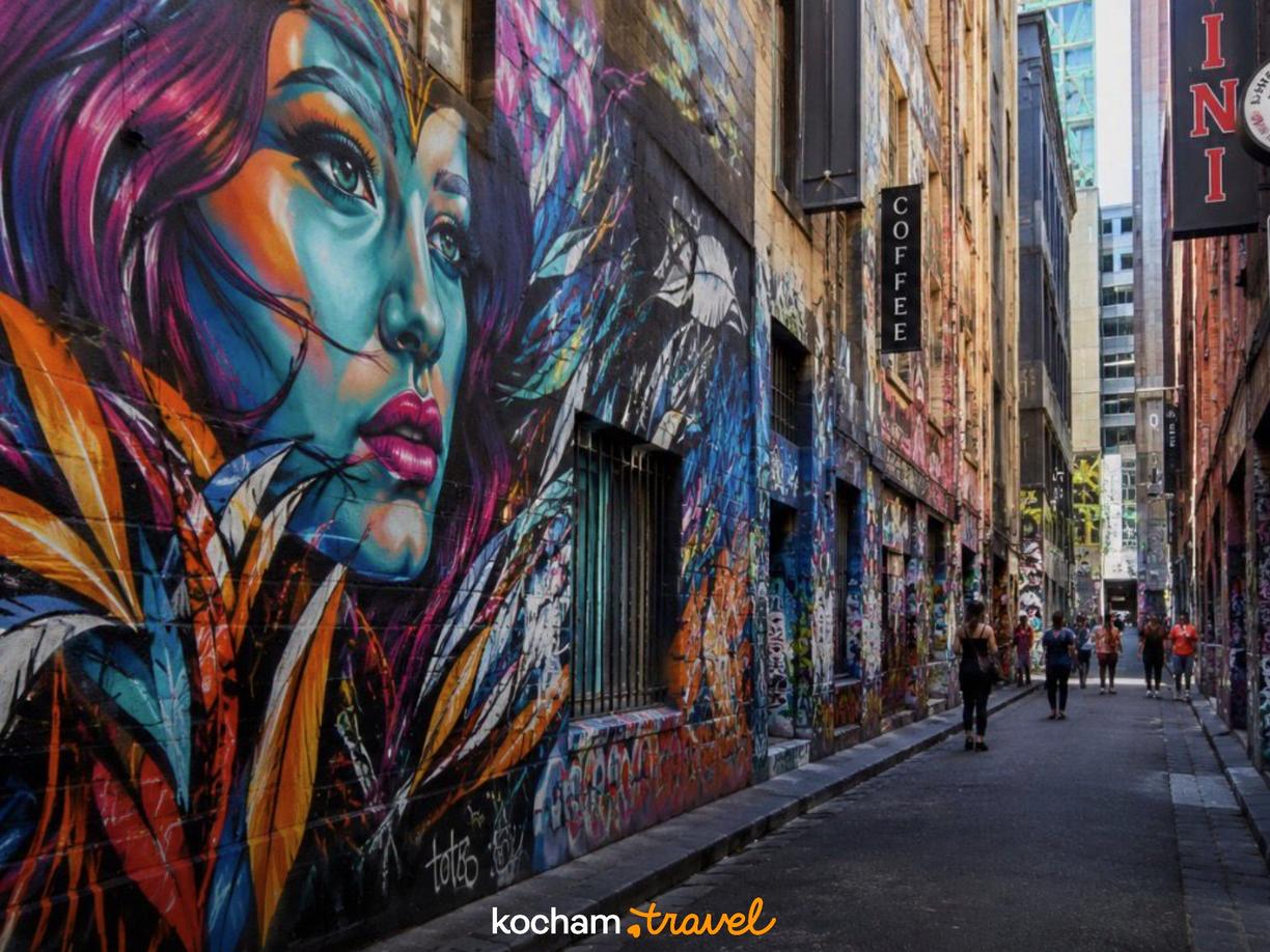 Kolorowy mural kobiety i graffiti w tętniącej życiem miejskiej uliczce.