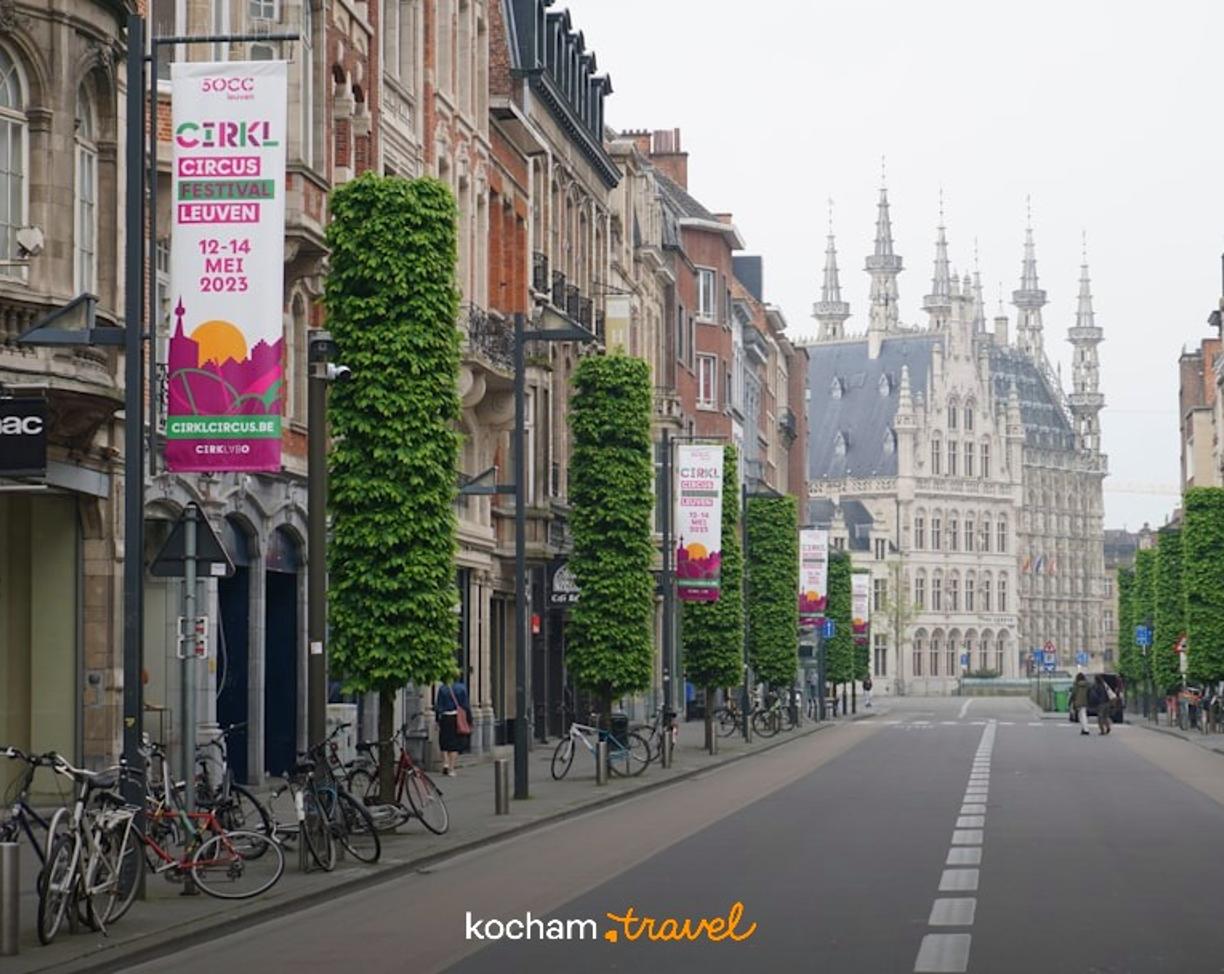 Zabytkowa ulica w Leuven, Belgia, z ratuszem i rowerami.