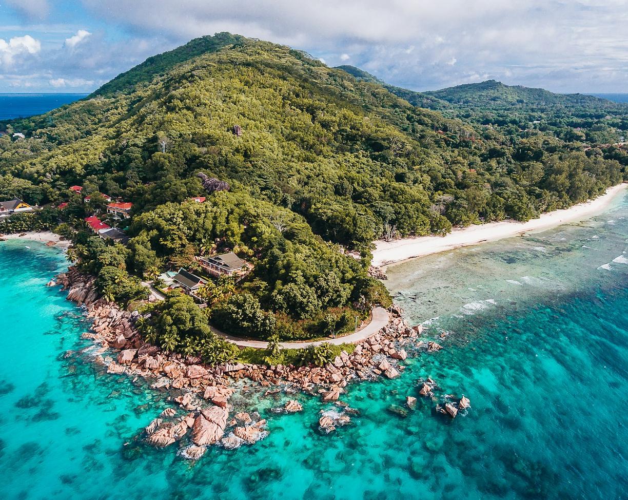 Tropikalna wyspa z zielonymi górami, skalistymi plażami i turkusowym oceanem.