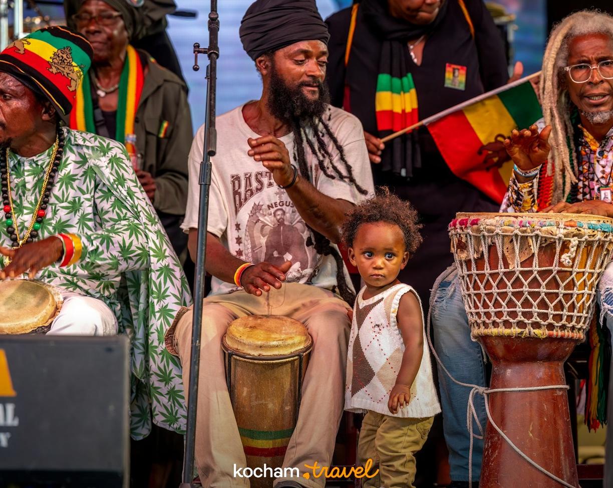 Rastafariańscy muzycy grający na bębnach, z dzieckiem obok.