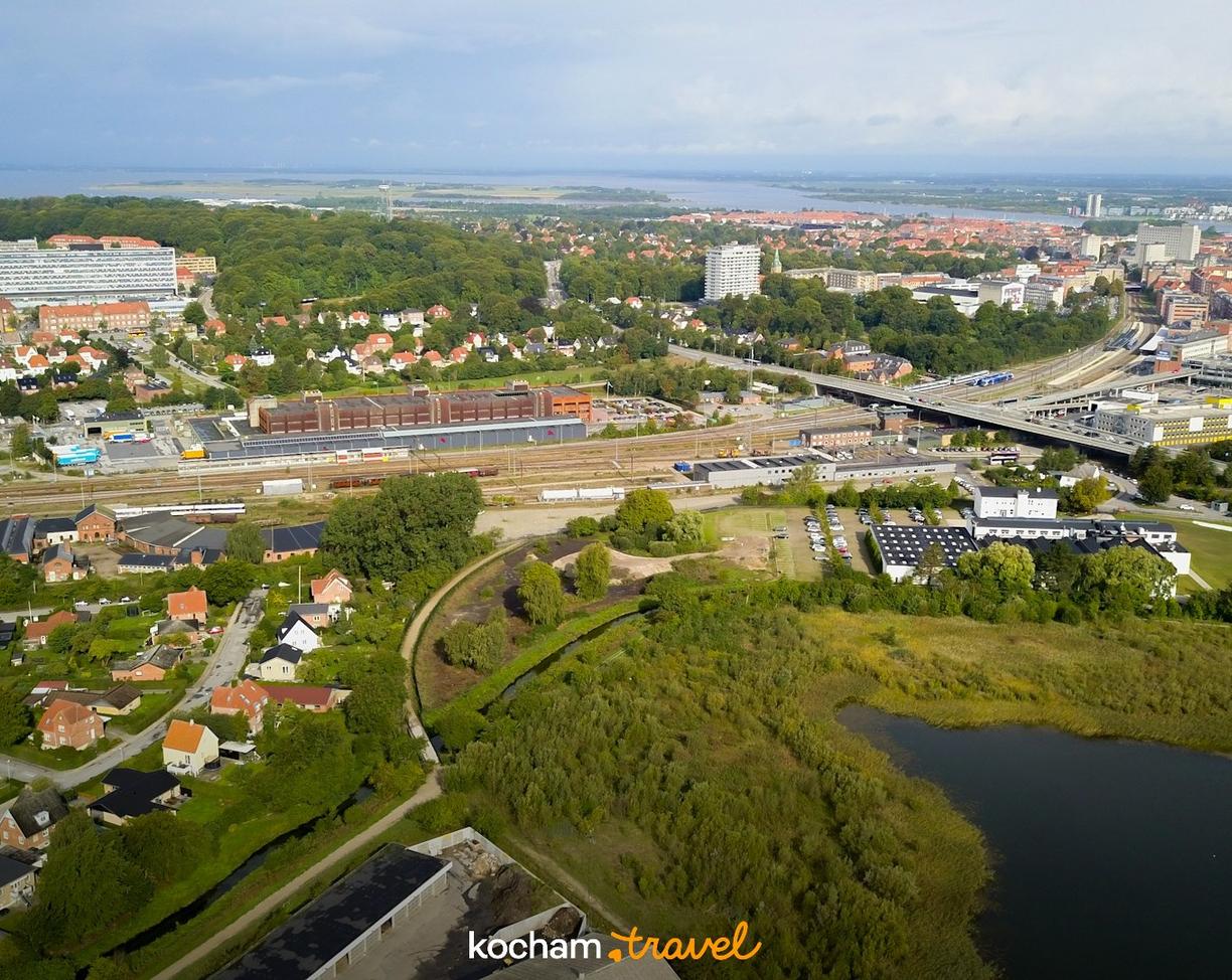 Miasto z lotu ptaka: zabudowania, zieleń, tory kolejowe i jezioro.