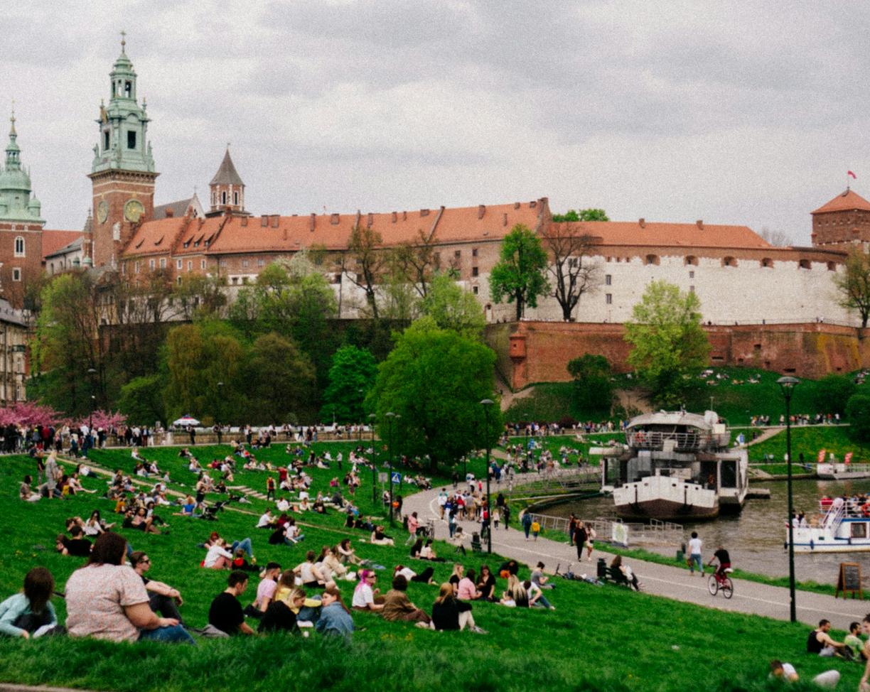 Zamek Wawelski w Krakowie, ludzie relaksujący się na trawie nad Wisłą.