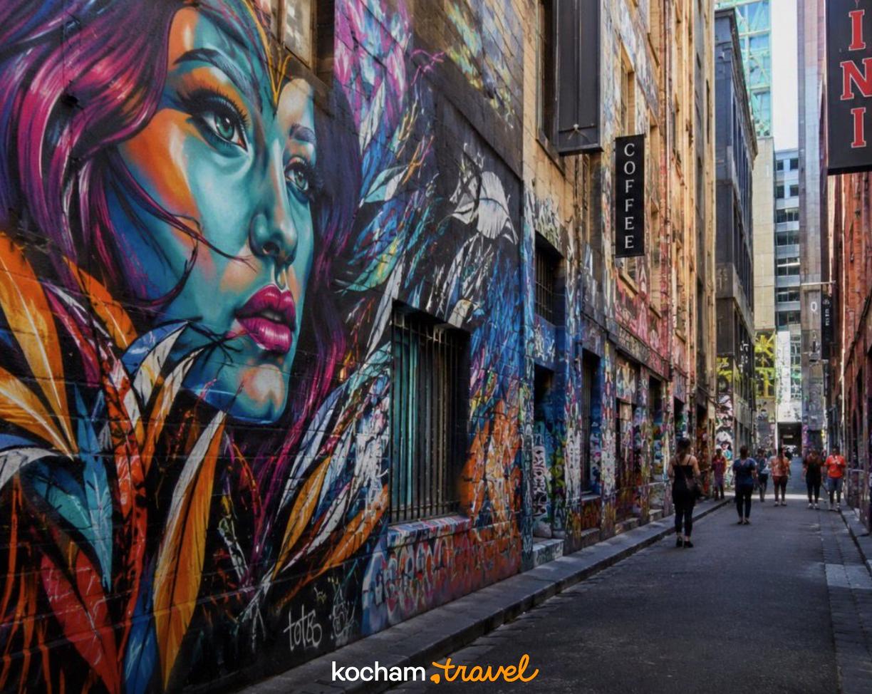 Kolorowy mural kobiety i graffiti w tętniącej życiem miejskiej uliczce.