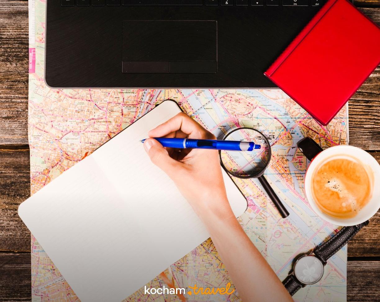 Planowanie podróży: notes, mapa, długopis, kawa i laptop.