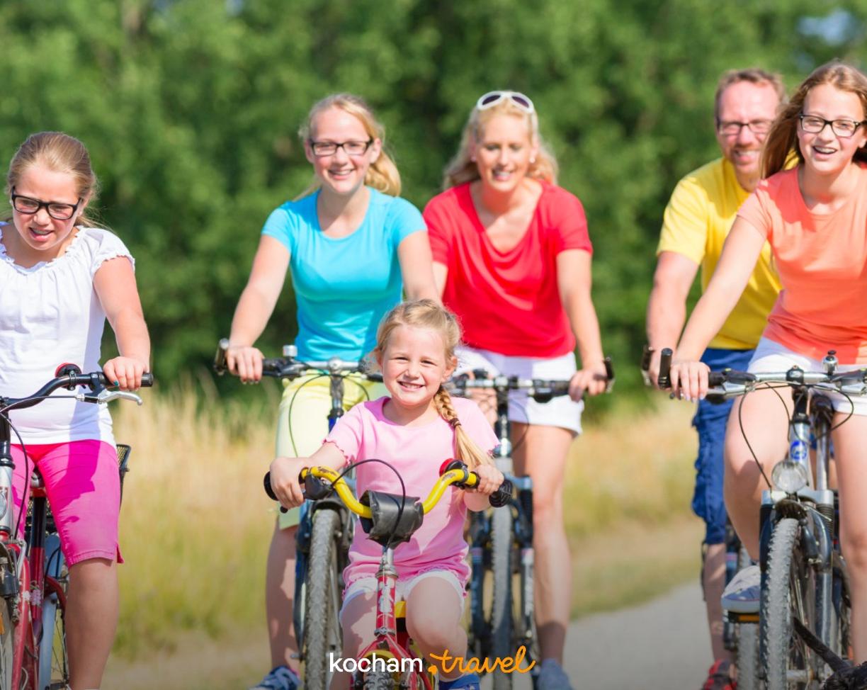 Uśmiechnięta rodzina aktywnie spędza czas na rowerach latem.