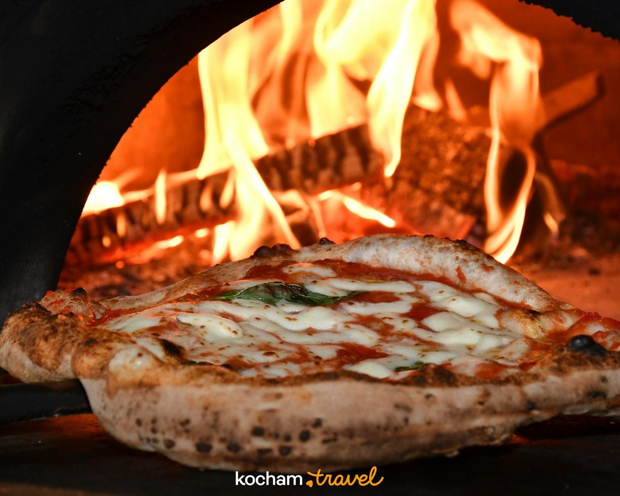 Klasyczna pizza Margherita pieczona w rozgrzanym piecu opalanym drewnem.