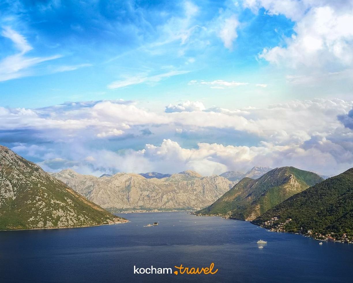 Panoramiczny widok zatoki otoczonej górami, z łodziami na wodzie.
