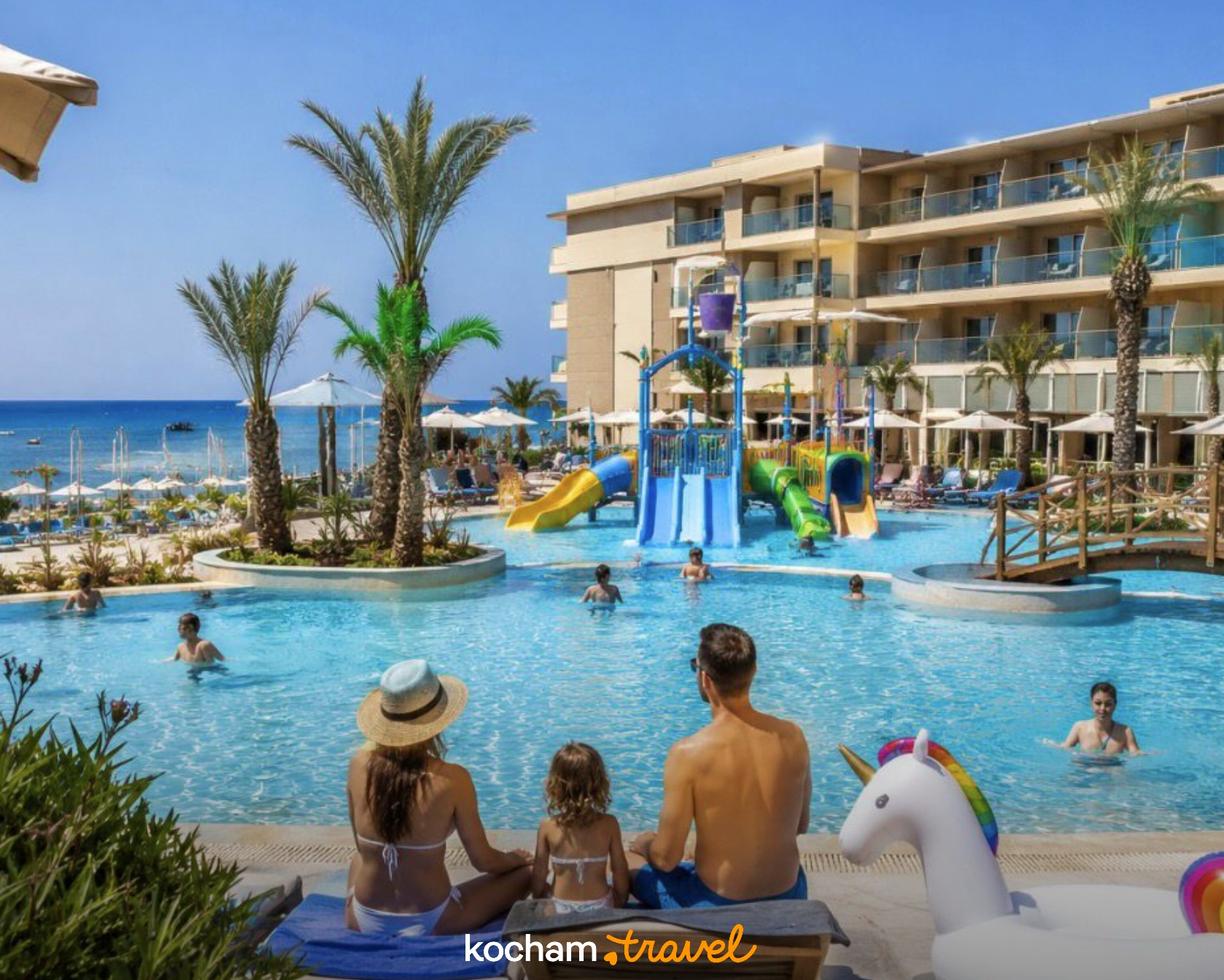 Słoneczne wakacje rodziny przy basenie hotelu z aquaparkiem i plażą.