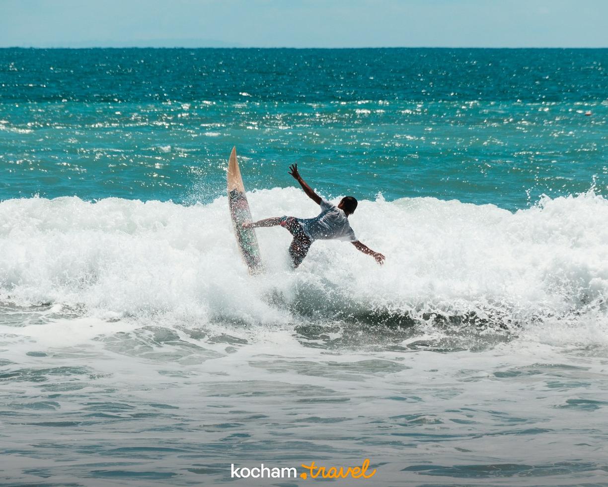Surfer balansujący na szczycie spienionej fali w błękitnym oceanie.