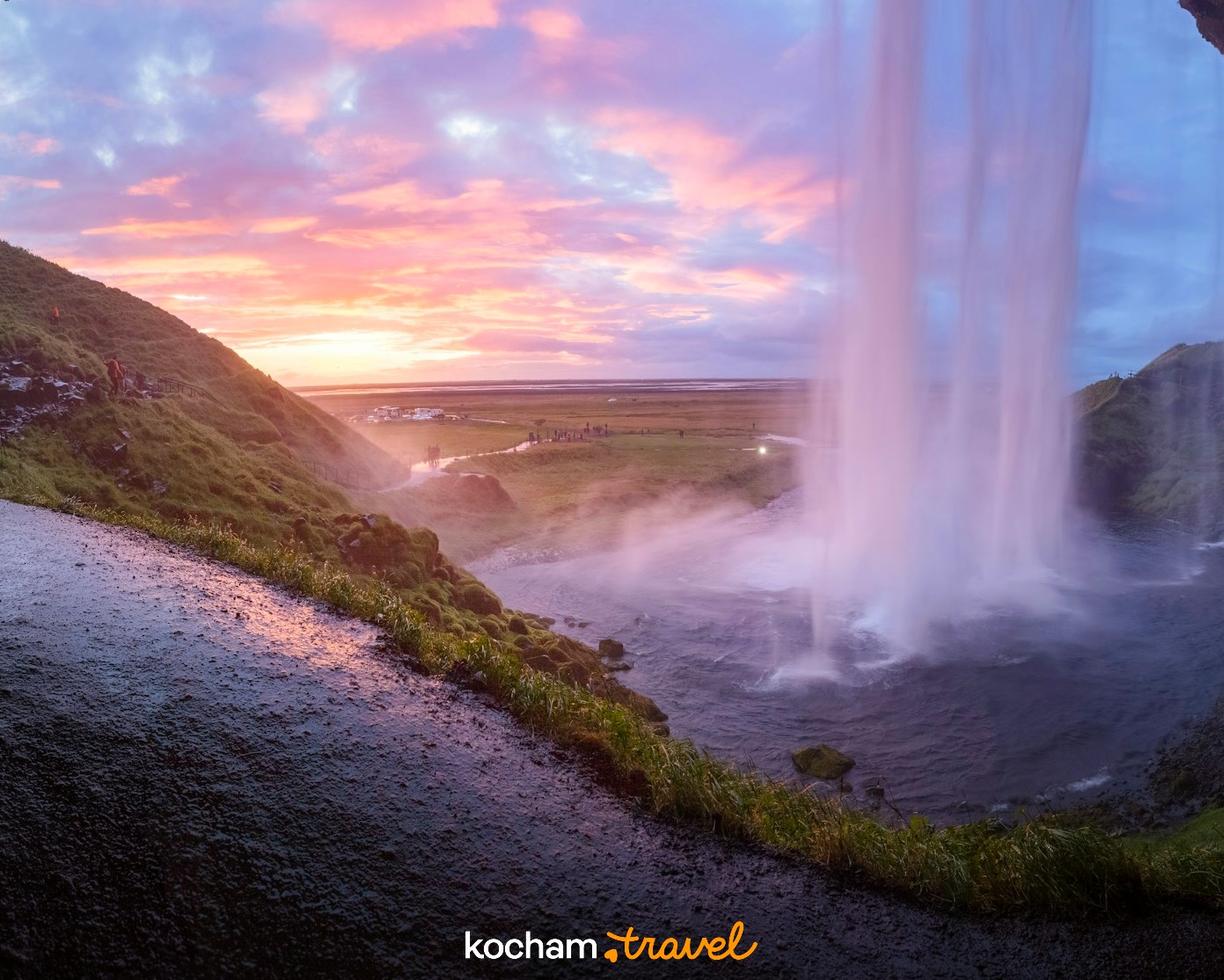Wodospad Seljalandsfoss w Islandii oglądany zza kaskady przy zachodzie słońca.
