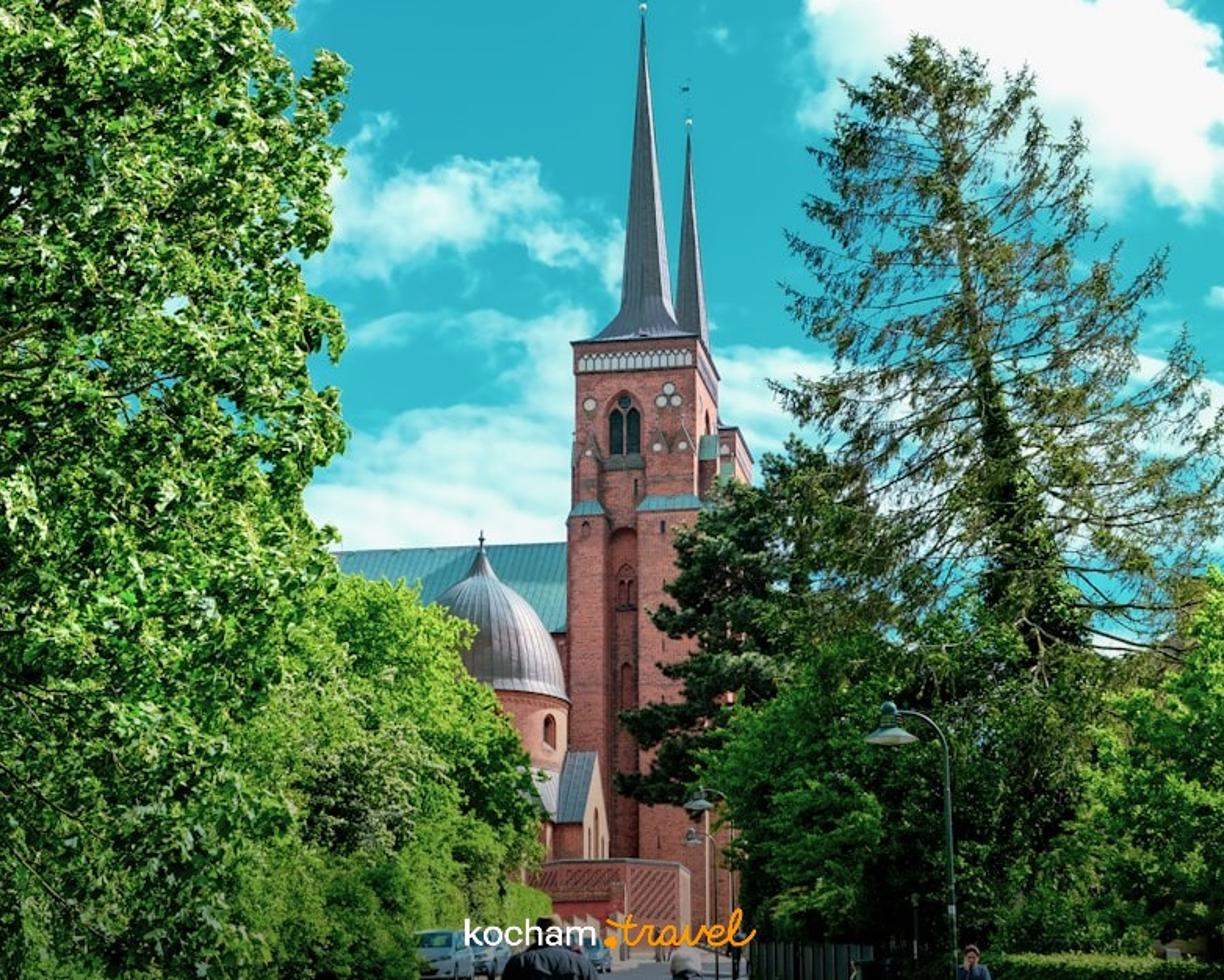 Katedra w Roskilde, Dania, gotycka architektura, uliczka, zieleń, ludzie.