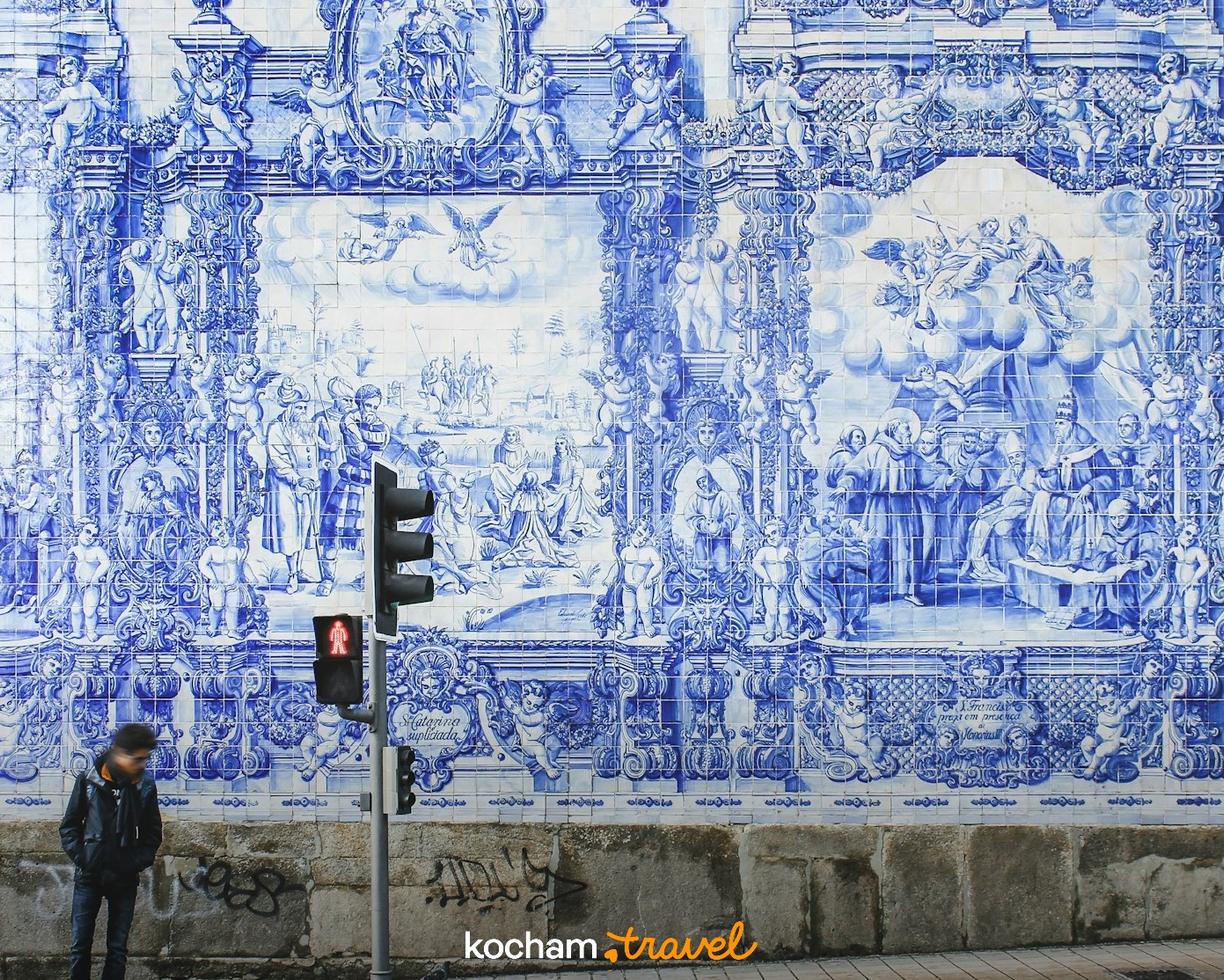 Niebiesko-białe azulejos na ścianie przedstawiające sceny historyczne w Porto.