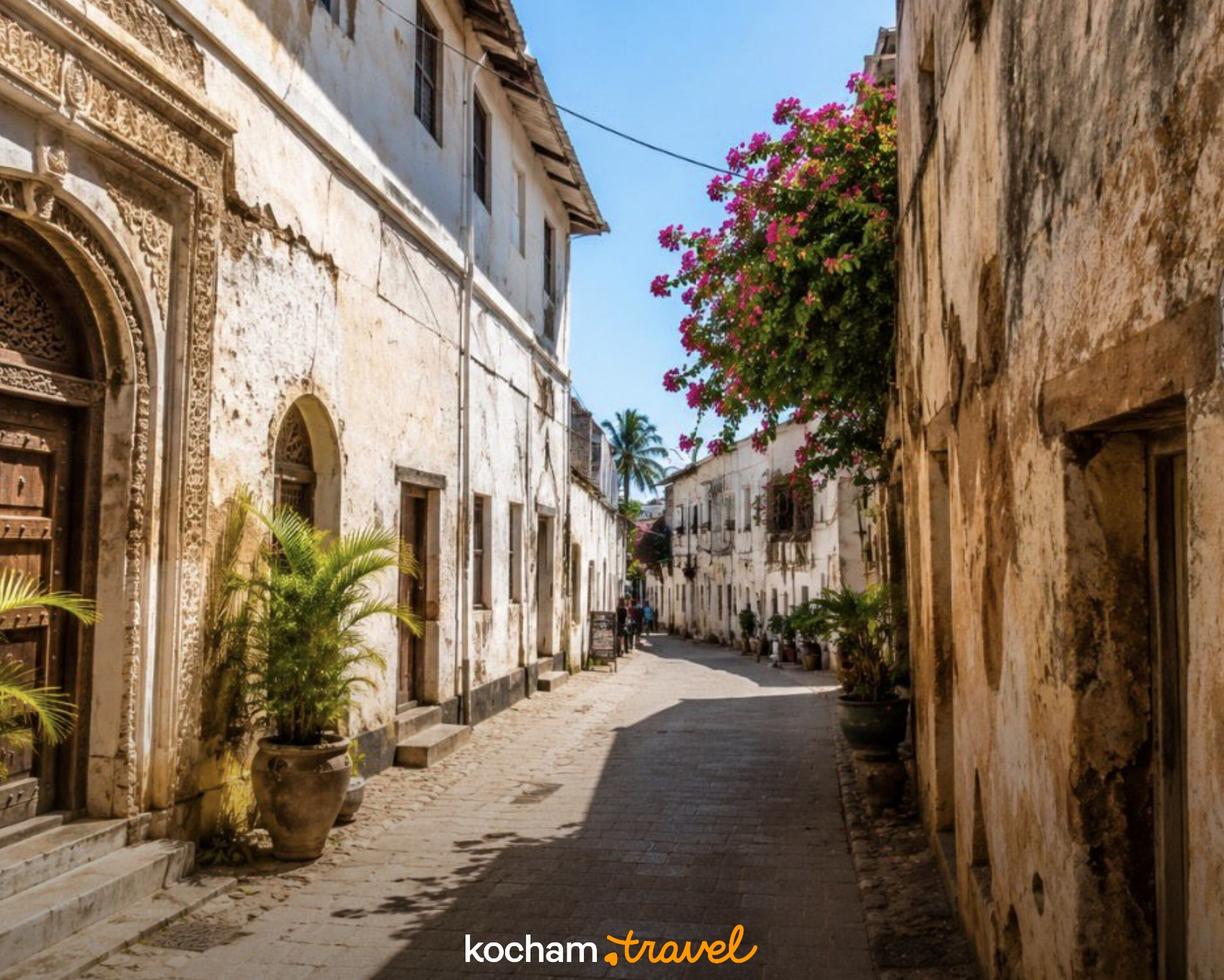 Kamienna uliczka z rzeźbionymi drzwiami i bugenwillą na Zanzibarze.