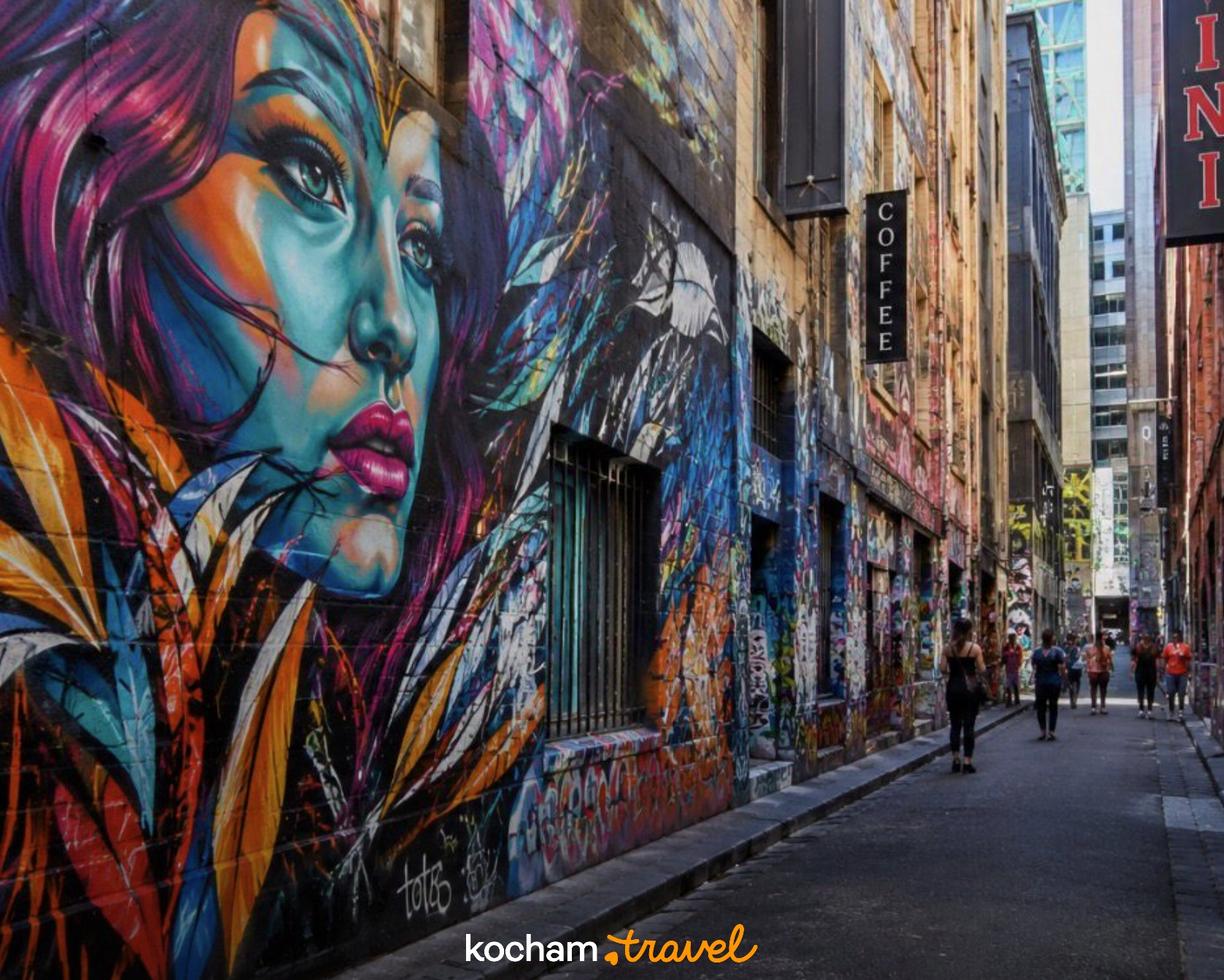 Kolorowy mural kobiety i graffiti w tętniącej życiem miejskiej uliczce.
