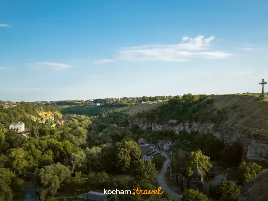 Panoramiczny widok zielonej doliny rzecznej, miasteczka i krzyża
