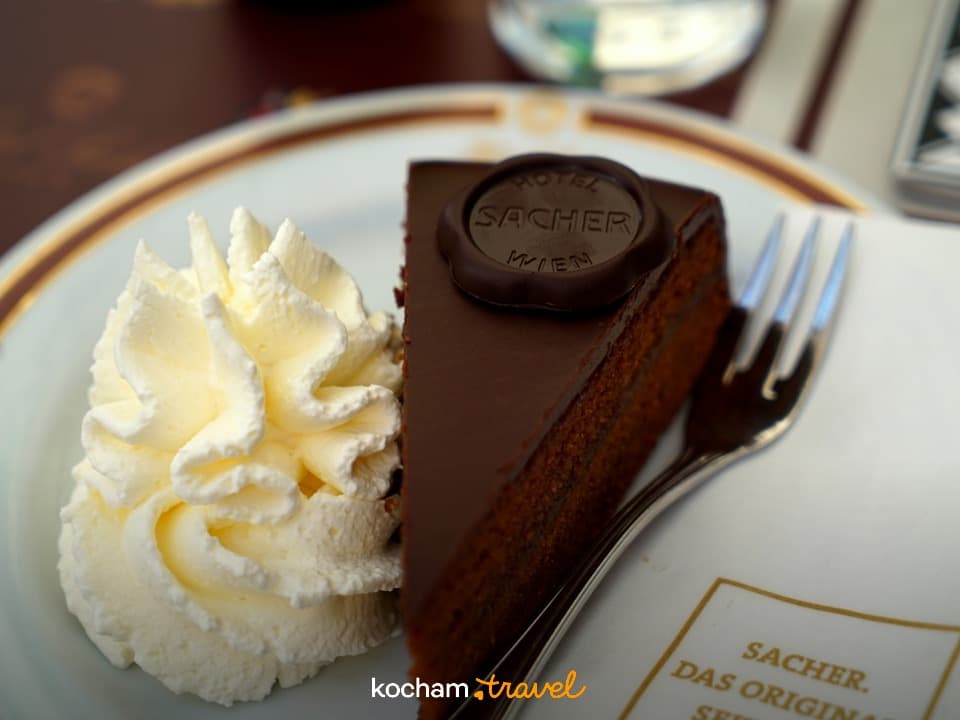 Sacher Torte z bitą śmietaną, wiedeński deser na talerzu.