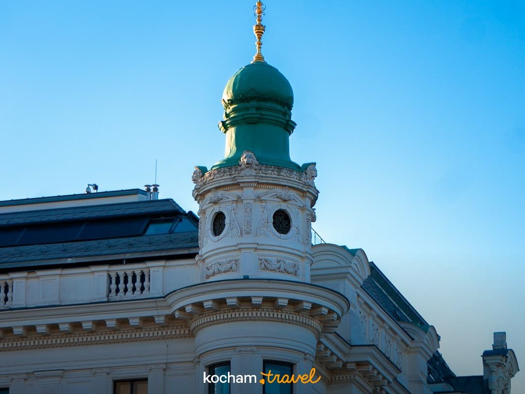 Architektura miejska, ozdobny budynek, zielona kopuła, błękitne niebo.
