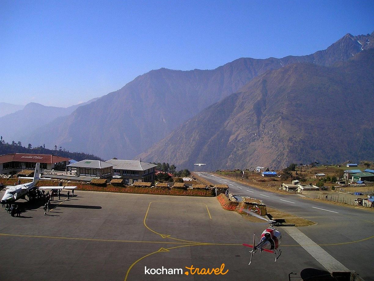 Lotnisko Lukla w Himalajach z samolotem, helikopterem i majestatycznymi górami.