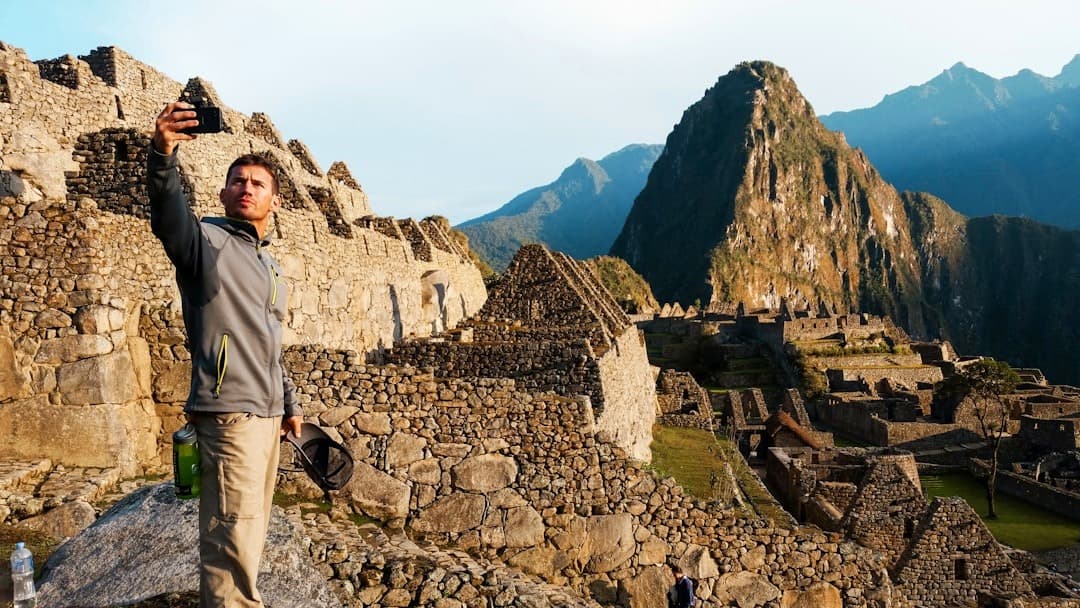 Mężczyzna robi selfie wśród starożytnych ruin Machu Picchu w Peru.