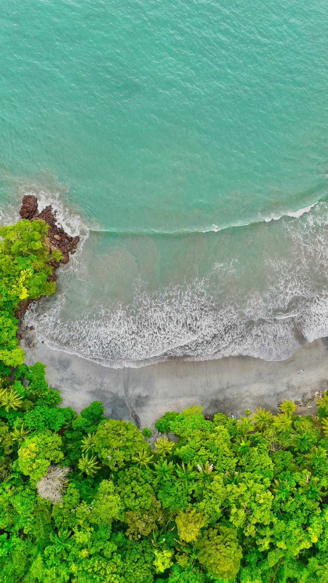 Widok z lotu ptaka na tropikalną plażę z dżunglą i turkusowym oceanem.