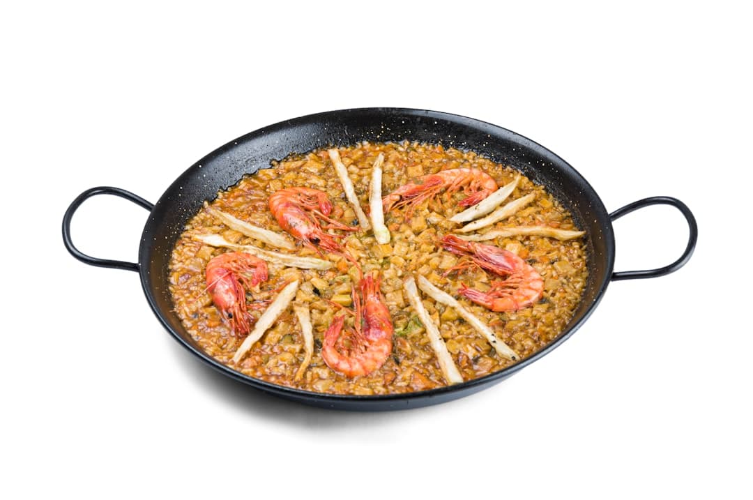 Paella z krewetkami i białą rybą w patelni.
