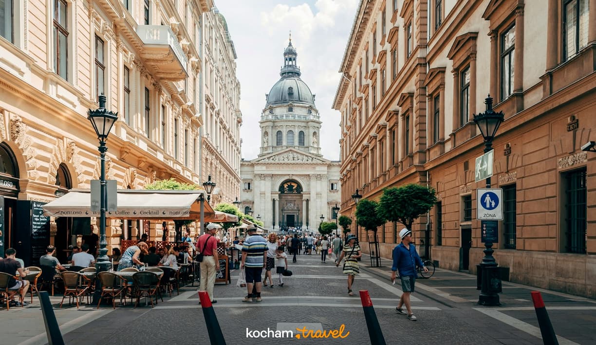 Słoneczna ulica Budapesztu z Bazyliką św. Stefana i kawiarniami na świeżym powietrzu.