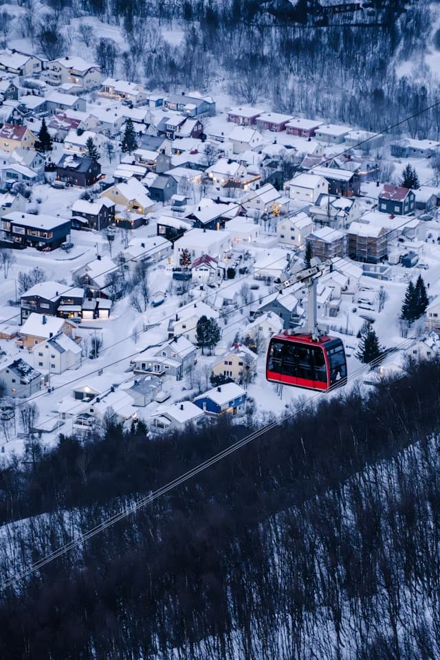 Czerwona gondola nad zaśnieżonym miasteczkiem w zimowym krajobrazie.
