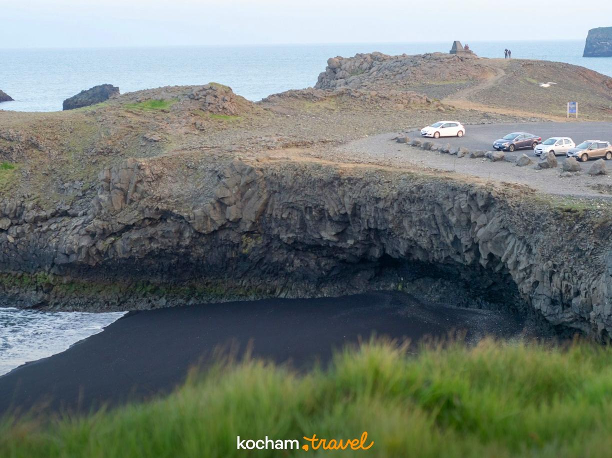 Czarna plaża, bazaltowe klify i parking nad oceanem na Islandii.