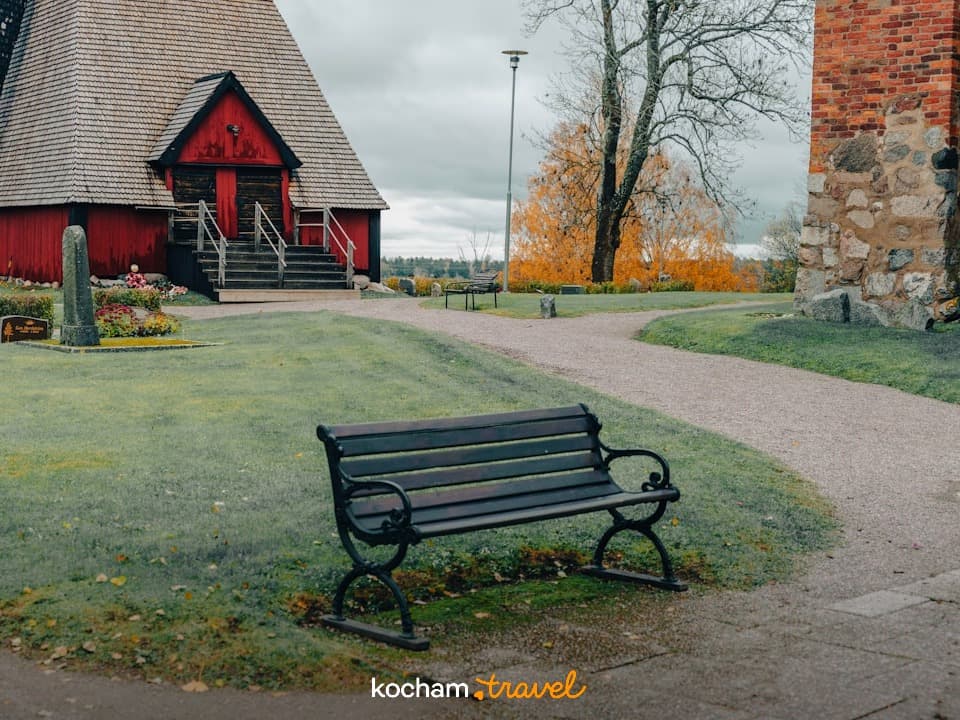 Czerwony drewniany kościół, zabytkowa architektura, cmentarz, ławka, jesień.