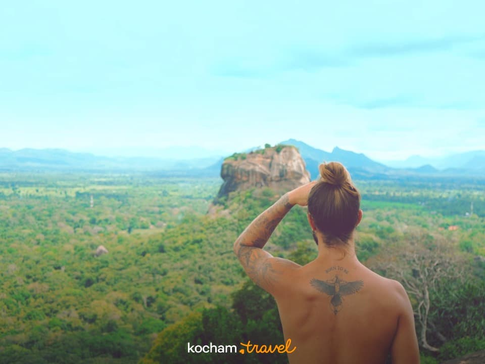 Mężczyzna podziwiający panoramiczny widok na Sigiriyę i zielony krajobraz Sri Lanki.