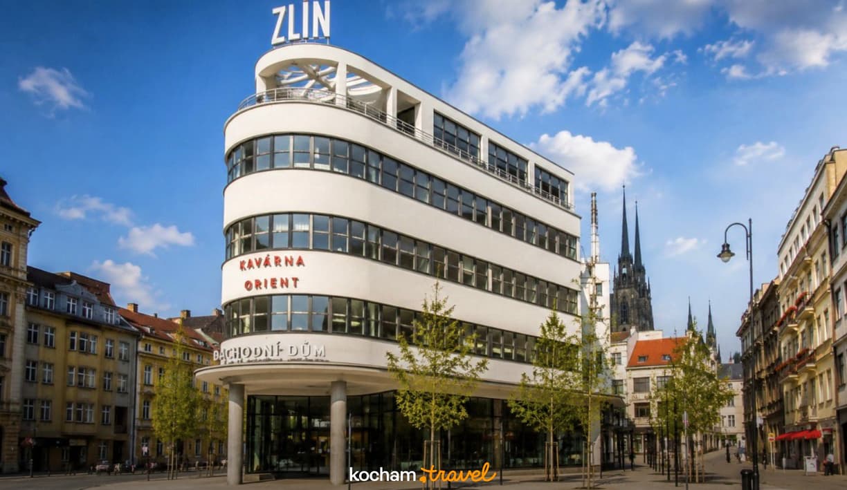 Biały funkcjonalistyczny budynek z napisem ZLIN w centrum Brna.