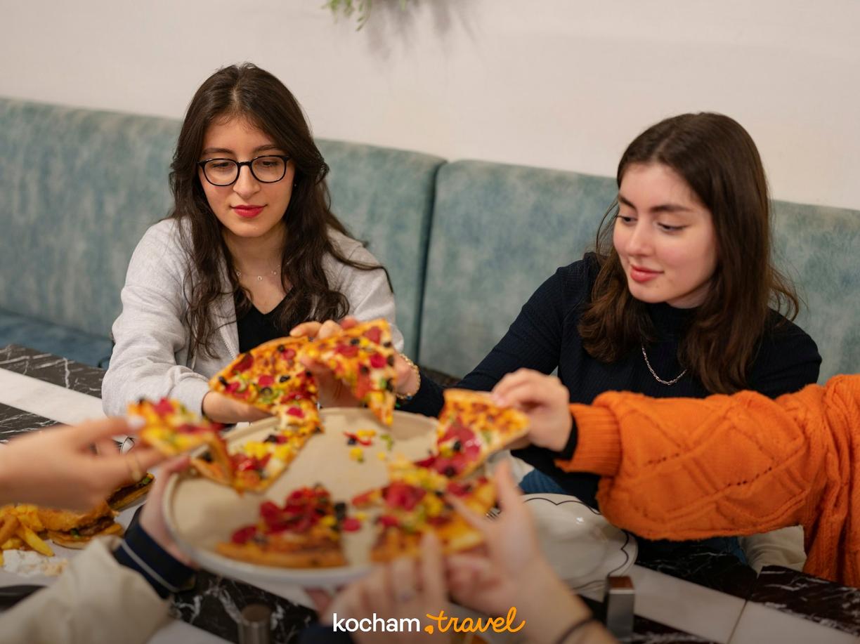Młodzi ludzie dzielący się pizzą w restauracji.