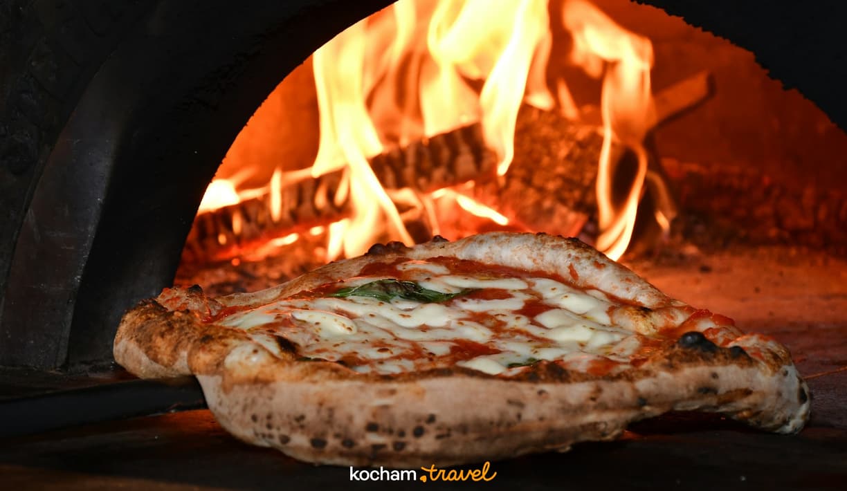 Klasyczna pizza Margherita pieczona w rozgrzanym piecu opalanym drewnem.