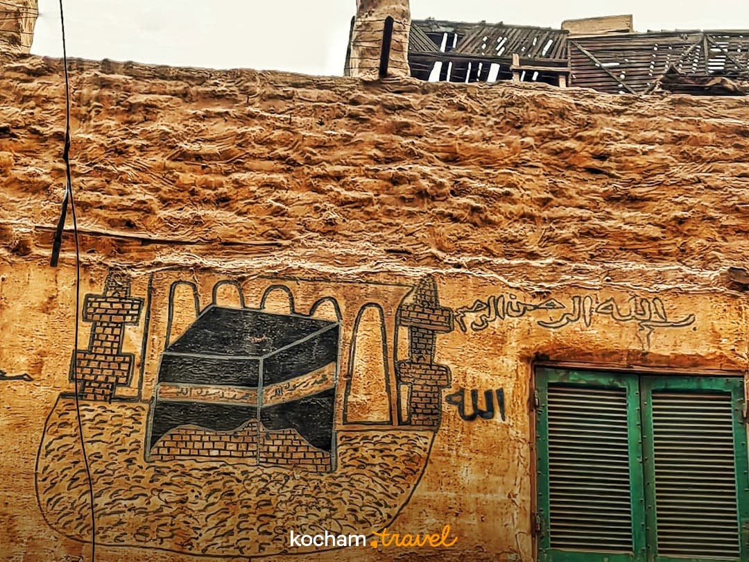 Mural Kaaby i arabskie pismo na starej ścianie z zielonym oknem.