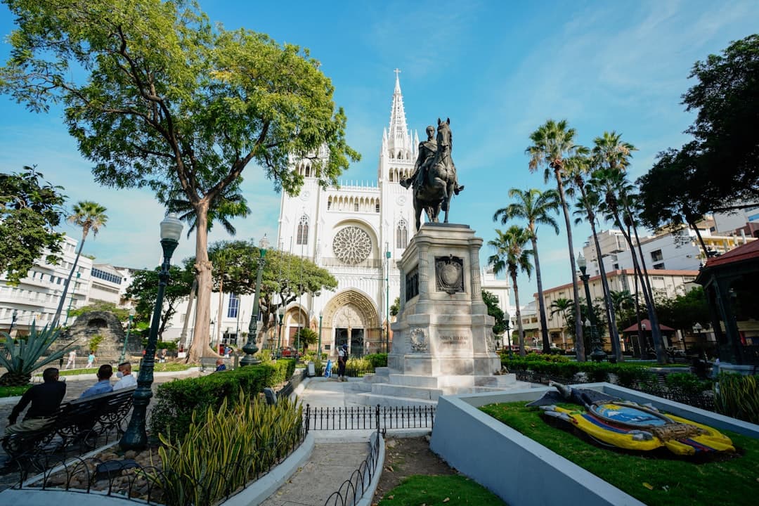 Katedra Metropolitalna Guayaquil, pomnik Bolivara, palmy, błękitne niebo w parku.