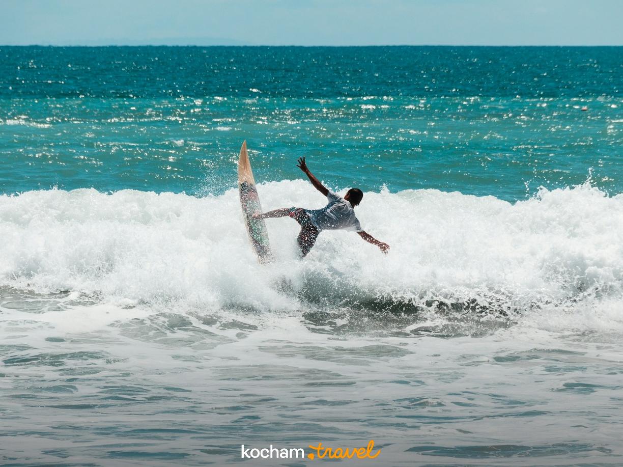Dynamiczny surfer skacze na desce po wzburzonej fali oceanu.