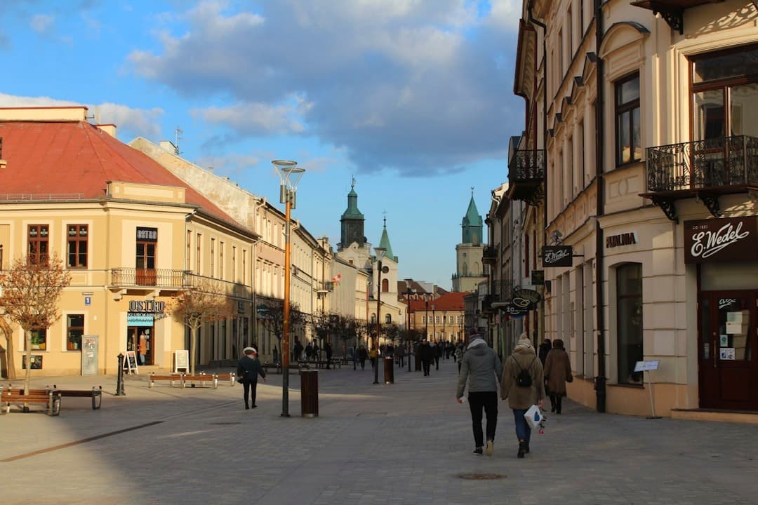 Słoneczny deptak w historycznym polskim mieście z zabytkowymi budynkami.