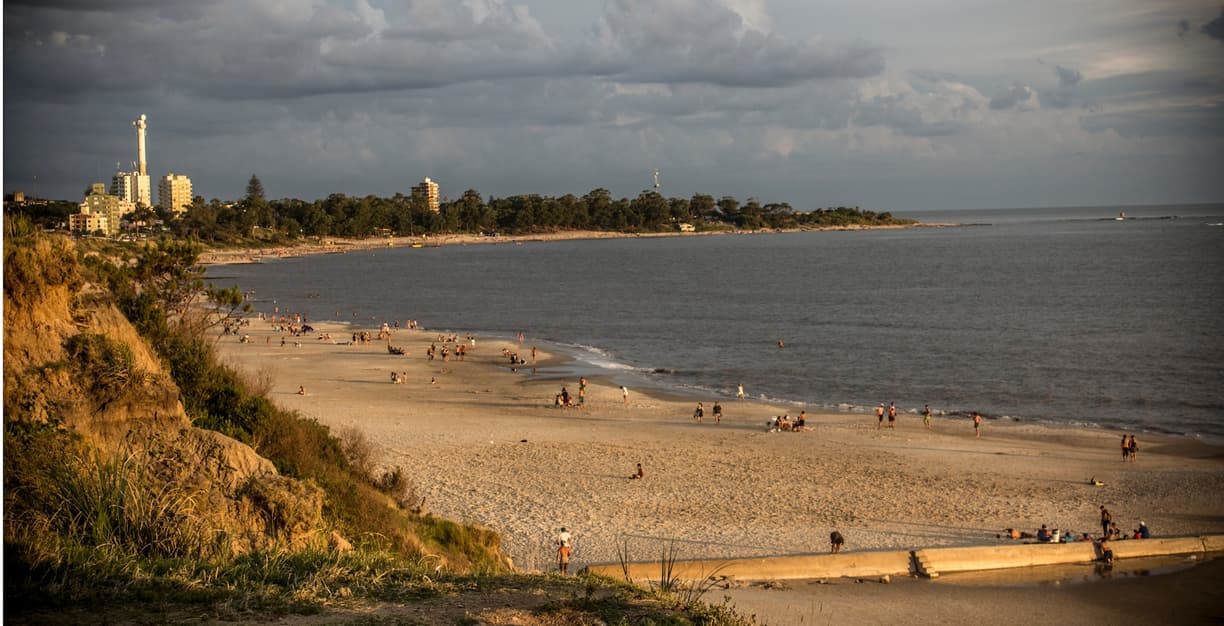 Złocista plaża z ludźmi, miasteczko nad morzem, dramatyczne chmury.