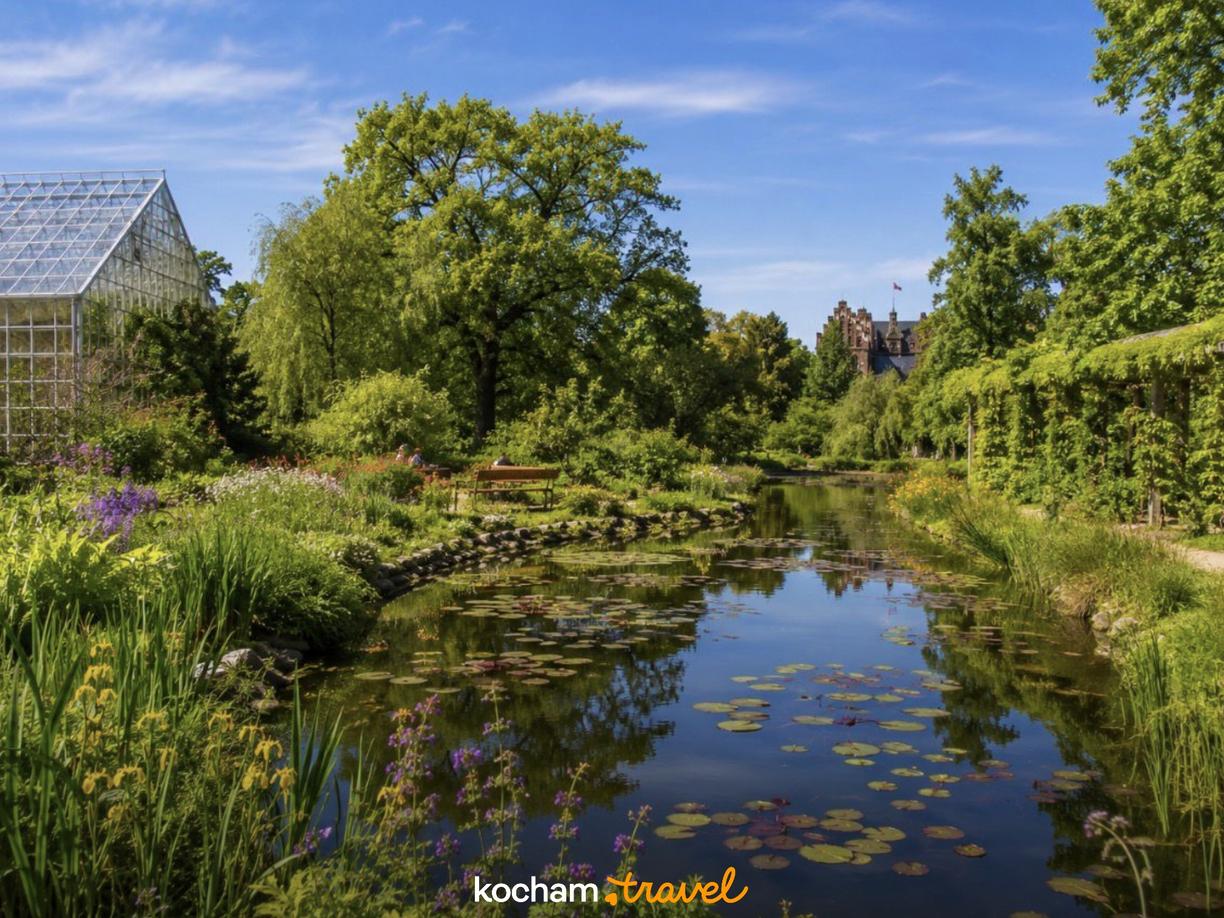 Letni ogród botaniczny ze stawem, zamkiem i szklarnią.