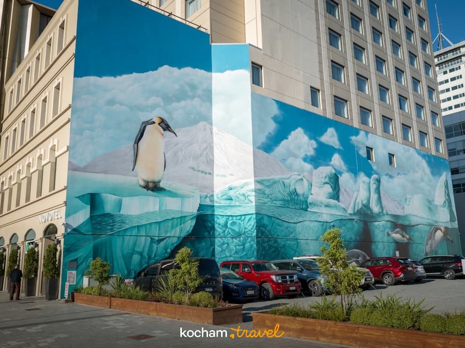 Mural z pingwinami i górami lodowymi na ścianie budynku Novotel w mieście.
